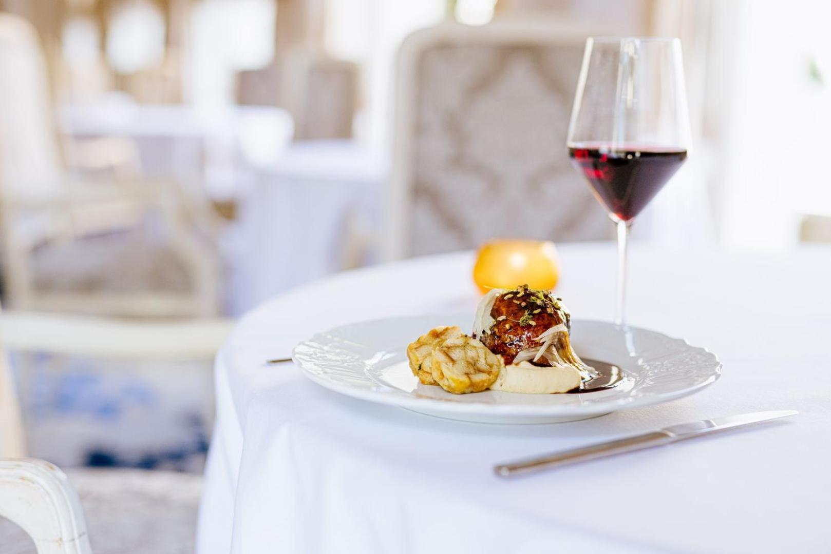 Grandhotel Pupp Karlsbad Buitenkant foto The photo shows a beautifully arranged dining table setting. On the table, there is a white plate containing two food items: one appears to be a meatball or similar dish, and the other looks like a golden-brown pastry or fritter. Accompanying the dis